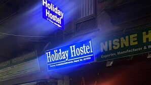 A Holiday Hostel with a blue sign, a closed blue shutter, and a red door. - Holiday Hostel (Kathmandu)