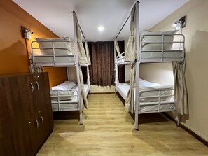 A room with bunk beds, a wooden wardrobe, and a wall-mounted light fixture. - Holiday Hostel (Kathmandu)