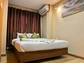 A hotel room with a bed, a painting on the wall, and an air conditioning unit. - Holiday Hostel (Kathmandu)