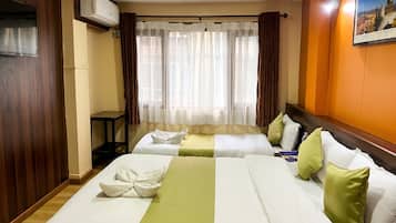 A hotel room with two beds, a window with sheer curtains, an air conditioning unit, and a framed picture on the wall.