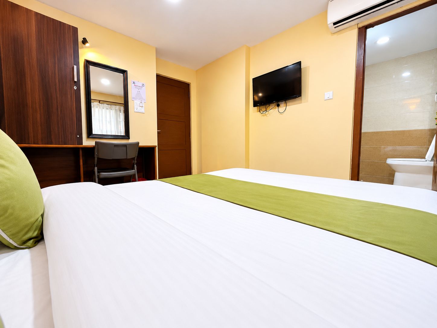 A hotel room with a bed, a desk, a chair, a television, and a bathroom.