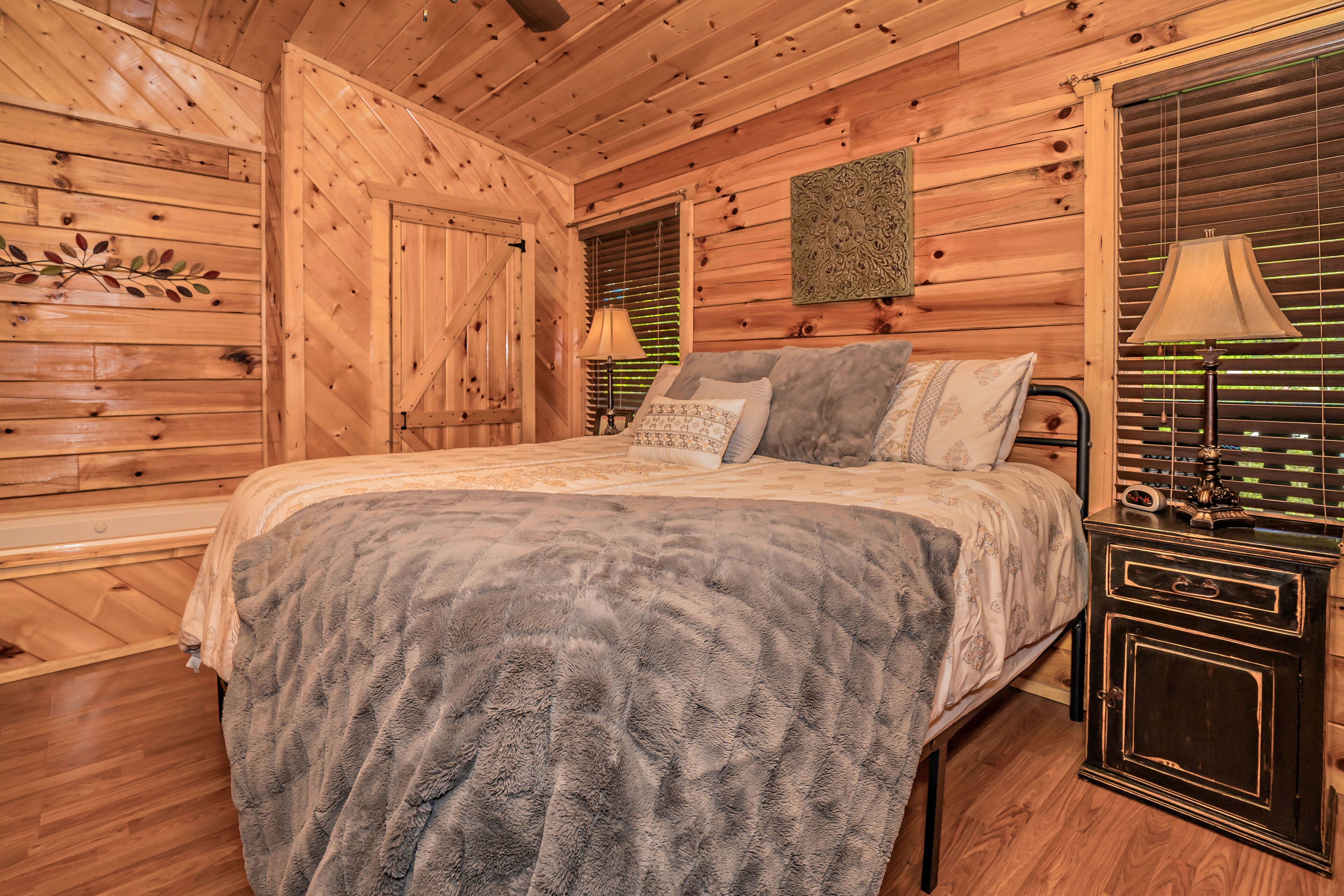 Un dormitorio de cabaña de madera con una cama, una mesita de noche y una lámpara de pared.