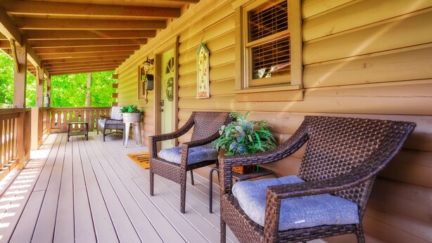 A wooden porch with wicker chairs and a bench, potted plants, and a small table. - Get Hip ~ Close 2 Attractions - Hot tub - Firepit - King Suite - Flat Drive (Sevierville)