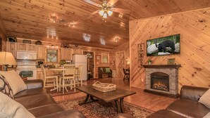 A cozy cabin interior with a fireplace, leather sofas, a dining area, and a kitchen. - Get Hip ~ Close 2 Attractions - Hot tub - Firepit - King Suite - Flat Drive (Sevierville)