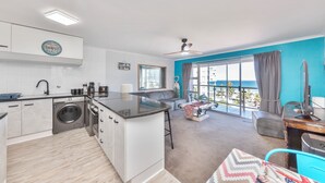 Eine moderne Küche mit Einbauwaschmaschine, einer Bar und einer Sitzecke mit Meerblick.