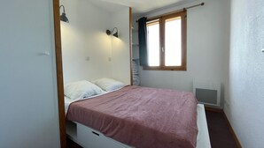 Una camera piccola con un letto singolo, una struttura in legno, una finestra con tenda e due luci a parete.