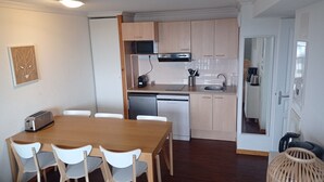 Una cucina compatta con zona pranzo, completa di forno a microonde, piano cottura e lavastoviglie.