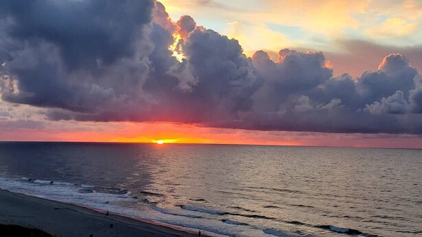 Um pôr do sol sobre o oceano com nuvens.