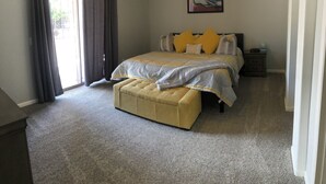 A bedroom with a bed, a bench, a nightstand, a painting, and a window with curtains. - Beautiful, newly renovated Tucson Eastside home  (Tucson)