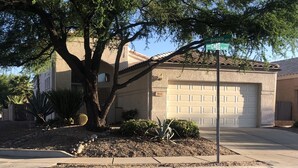 A residential house with a garage, a large tree in front, and a street sign indicating 'Camino Bengalá 8500 S' and 'Calle Cadiz 10,300 E'. - Beautiful, newly renovated Tucson Eastside home  (Tucson)