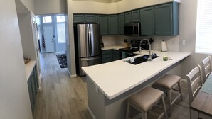 A modern kitchen with teal cabinets, stainless steel appliances, and a white countertop. - Beautiful, newly renovated Tucson Eastside home  (Tucson)