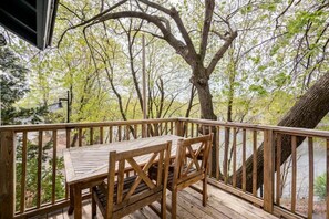 A wooden deck with a table and chairs, surrounded by trees. - The Railway Bridge Cottage (Catskill)