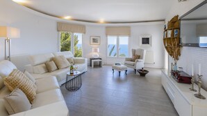 Un salon spacieux avec un canapé blanc, une table basse et une vue sur la mer.
