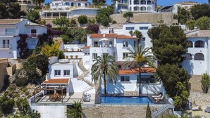 Un quartier résidentiel en bord de mer, avec des bâtiments blancs, une piscine et des palmiers.