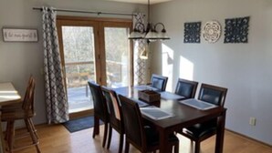 Un'area pranzo con tavolo e sedie in legno, una finestra con tende e decorazioni a parete.