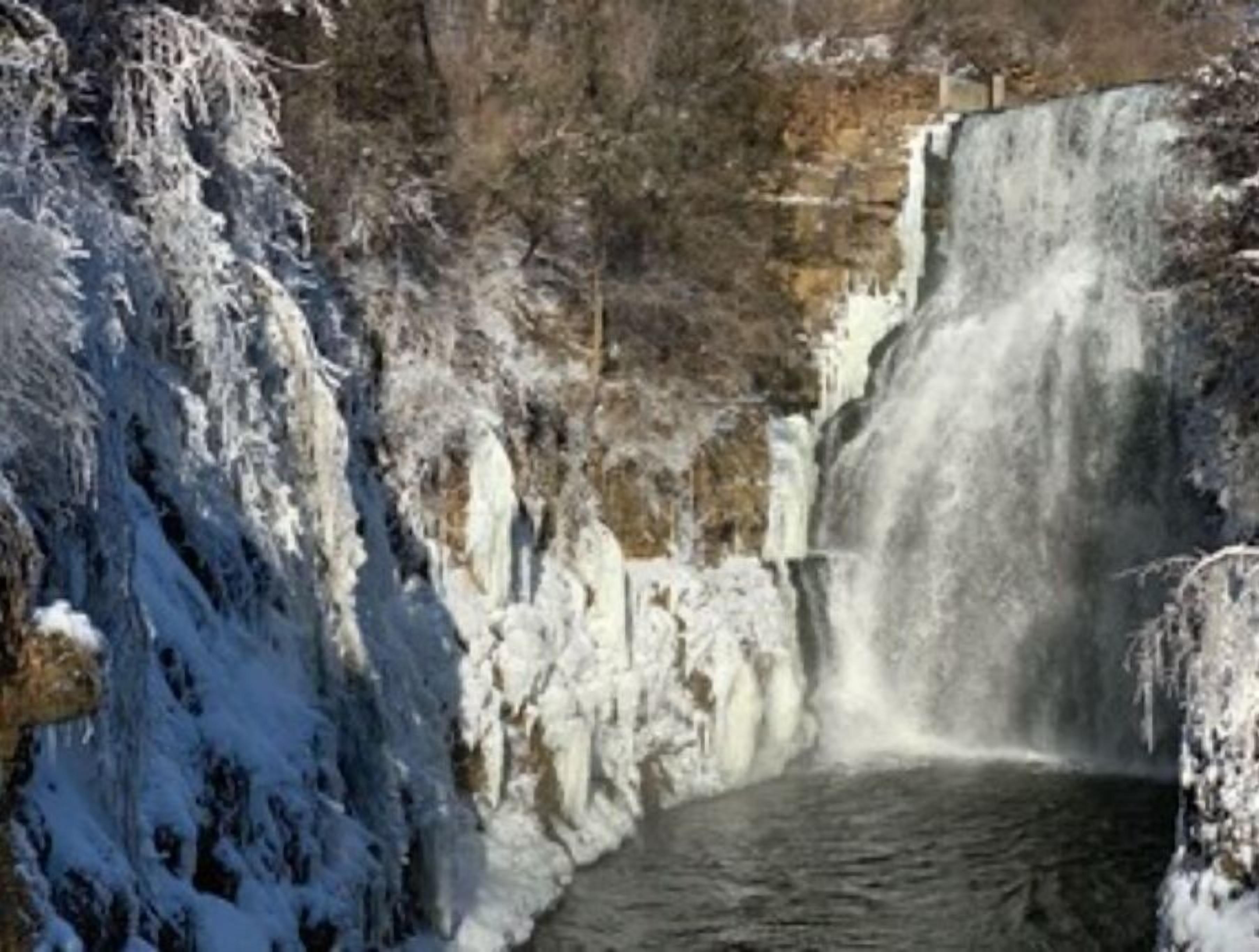 Ein Wasserfall mit Eisformationen und einem klaren Wasserlauf.