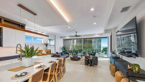 A modern kitchen with a central island, dining area with wooden chairs, and a living space with sofas and a coffee table. - #1 Rooftop Deck w/ Gulf Views - Steps to Beach (Siesta Key)