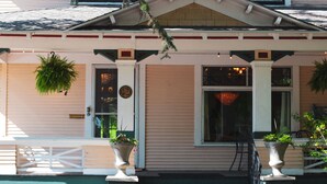 A building with a porch, potted plants, and a door with a sign. - Marianna Stoltz House (Spokane)