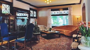 A cozy living room with a patterned carpet, a blue chair, a brown sofa, and a coffee table. - Marianna Stoltz House (Spokane)
