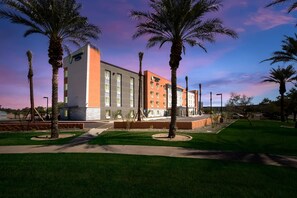 A modern building with a flat roof, rectangular windows, and a mix of orange and grey exterior walls.