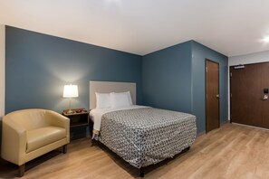 Ein Schlafzimmer mit Bett, Nachttisch, Lampe, Stuhl und Kleiderschrank.