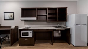 A compact kitchen with a built-in microwave, a refrigerator, and a sink. - Woodspring Suites Chandler Airport (Chandler)
