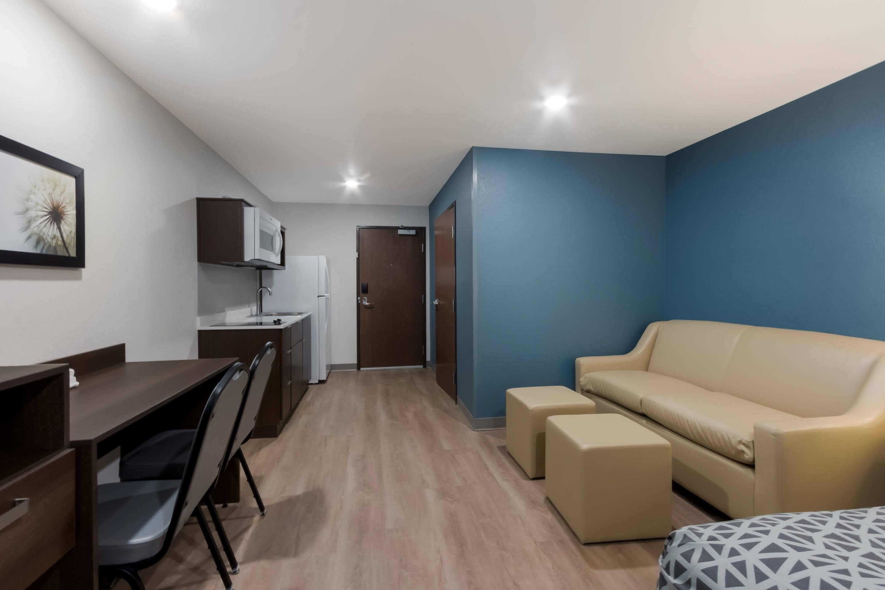 Een compacte kamer met kitchenette, een bank en een eethoek.