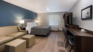 A hotel room with a bed, a desk, a chair, a sofa, and a TV. - Woodspring Suites Chandler Airport (Chandler)