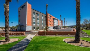 A modern hotel with a two-story structure, a parking lot, and well-maintained landscaping. - Woodspring Suites Chandler Airport (Chandler)