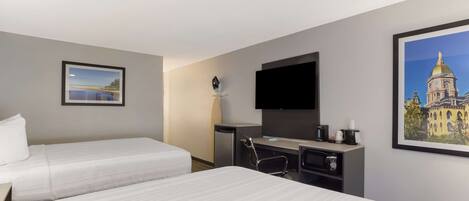 A hotel room with two beds, a desk with a chair, a flat-screen TV, and a coffee maker.