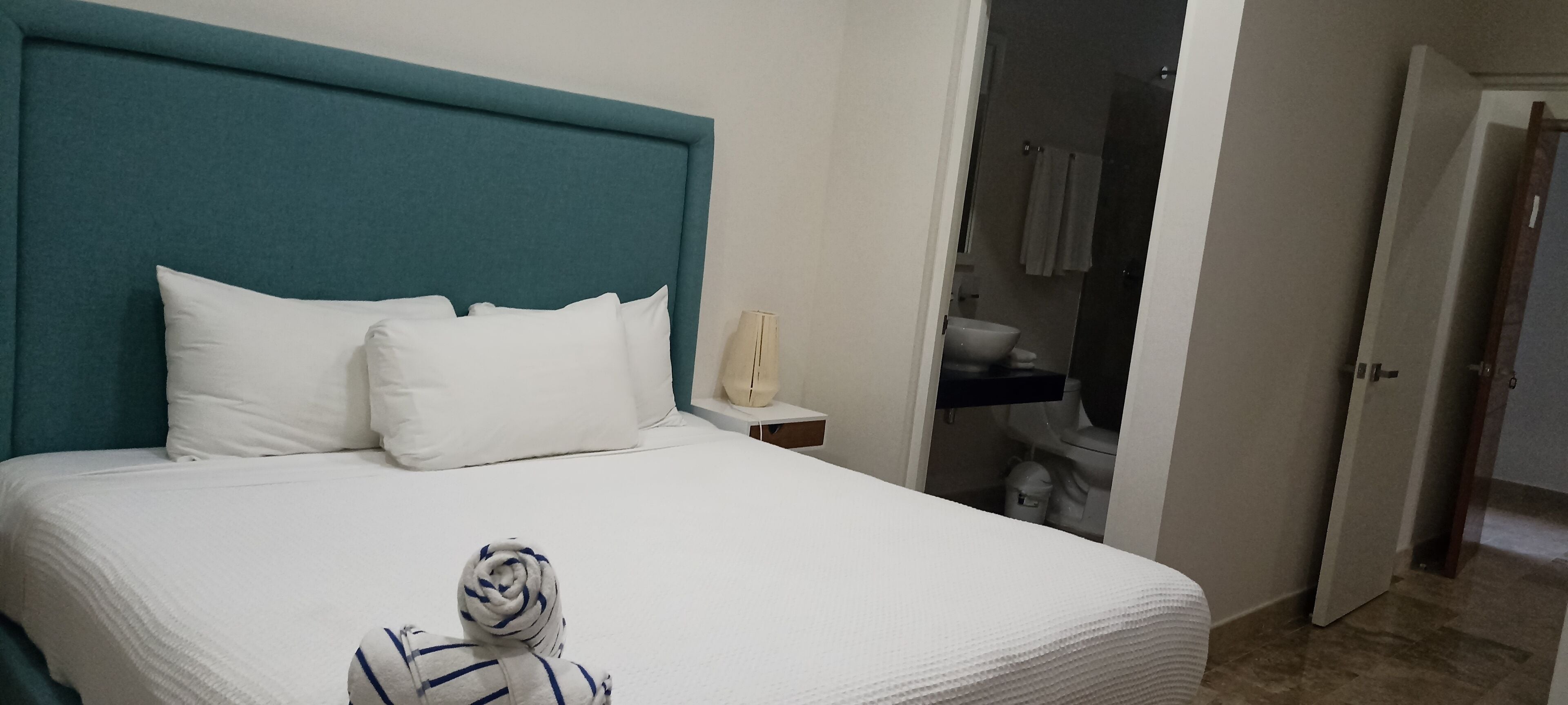 A neatly made bed with white bedding and a teal headboard.
