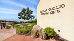 The exterior of the George L. Graziadio Executive Center with a clear view of the surrounding landscape, including a tree and a pathway leading to the entrance.
