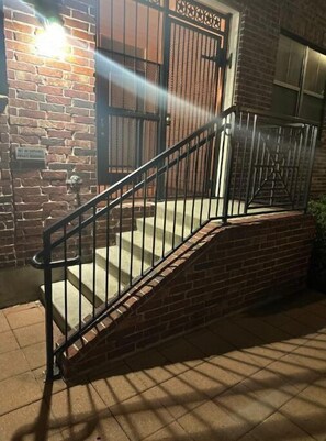 Enter a residence through the secure entrance, marked by a metal gate and brick wall.