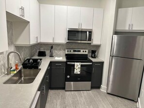 Modern kitchen with stainless steel appliances, white cabinetry, and a herringbone-patterned backsplash.