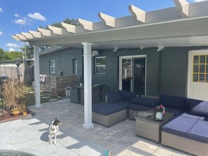 Relax on the patio under a covered pergola with comfortable seating and a beautiful garden view.