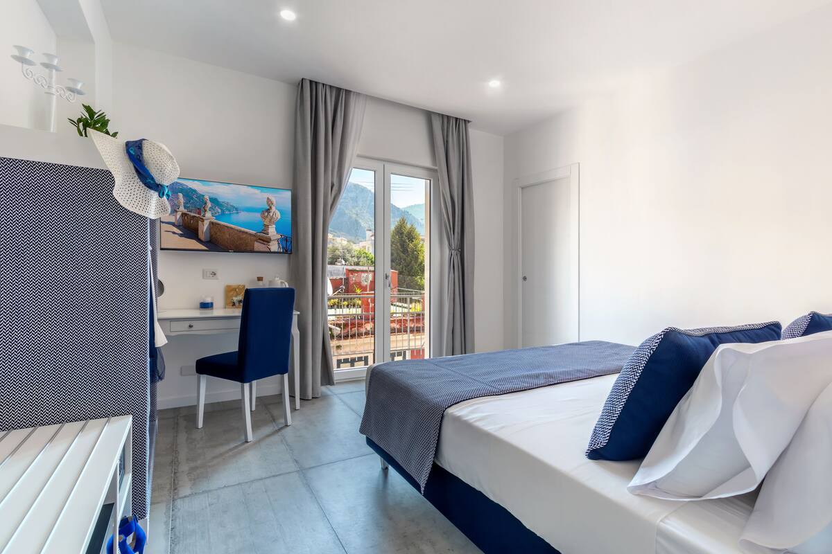 Ein Hotelzimmer mit Bett, Schreibtisch, Stuhl, Fernseher und einem Balkon mit Blick.