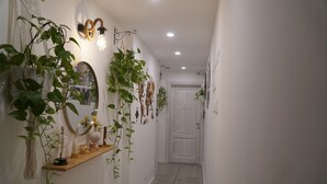 Un couloir avec une étagère en bois, des miroirs fixés au mur et des plantes suspendues.