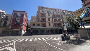 Une rue pavée avec un passage pour piétons menant à un immeuble à plusieurs étages doté de balcons.