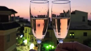 Deux flûtes à champagne sur un balcon, avec vue sur la ville au crépuscule.