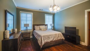 A bedroom with a wooden bed, two bedside lamps, a TV, and a dresser. - Cozy Jackson Vacation Rental < 1 Mi to University (Jackson)