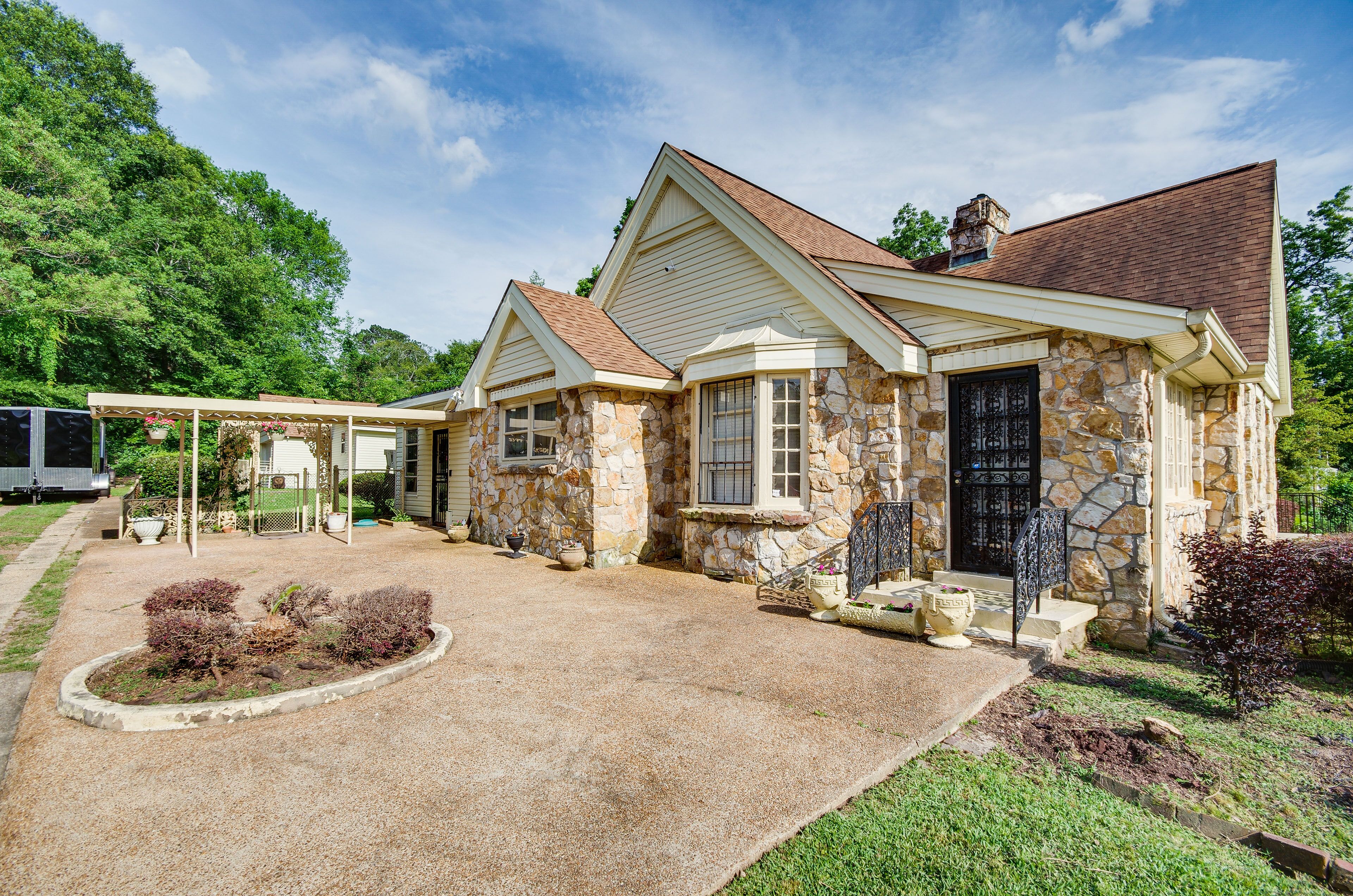 A stone house with a covered porch and a gravel driveway.