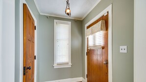 A hallway with wooden doors, a window with blinds, and a ceiling light fixture. - Cozy Jackson Vacation Rental < 1 Mi to University (Jackson)