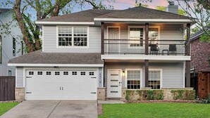 A two-story house with a garage, a balcony, and a well-maintained lawn.