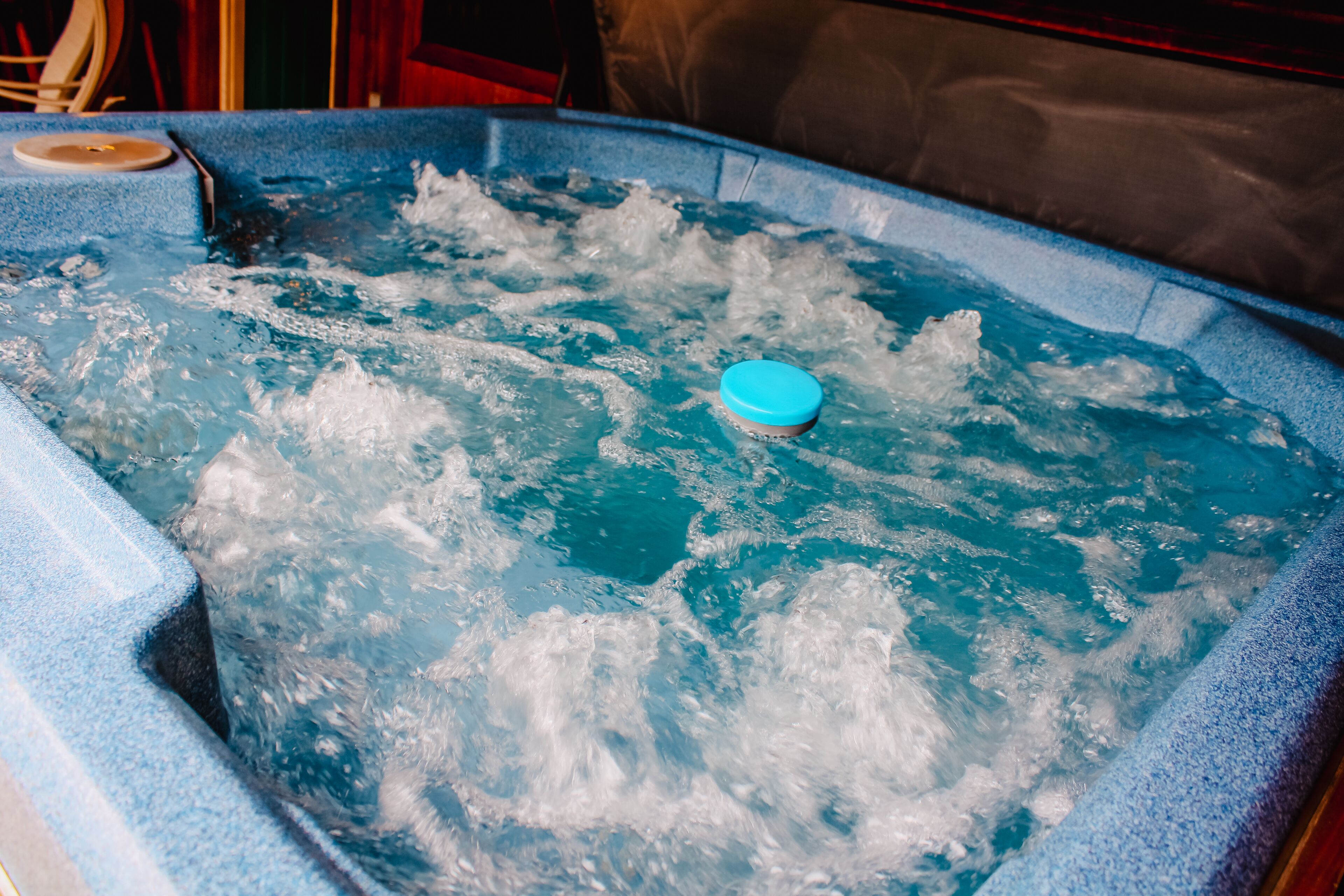 Un jacuzzi con tapa azul y burbujas visibles, lo que indica que está en uso.