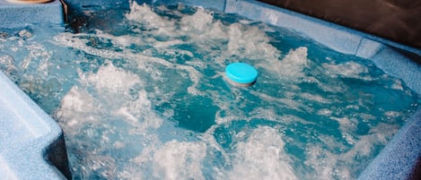Un jacuzzi con tapa azul y burbujas visibles, lo que indica que está en uso.