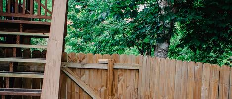 A wooden fence with a gate, a wooden staircase, and a dirt ground area.