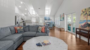 A spacious living room with a grey sectional sofa, a white coffee table, and a dining area in the background. - Anna Maria Guest House 401- 3 bedrooms in the middle of everything- 2 night mini (Anna Maria)
