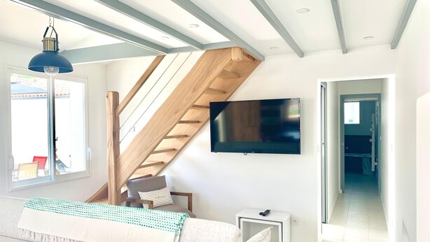 A modern living room with a staircase, a flat-screen TV, and a sofa. - CAPUCINE (6 chemin des Biches, La Couarde) (La Couarde-sur-Mer)
