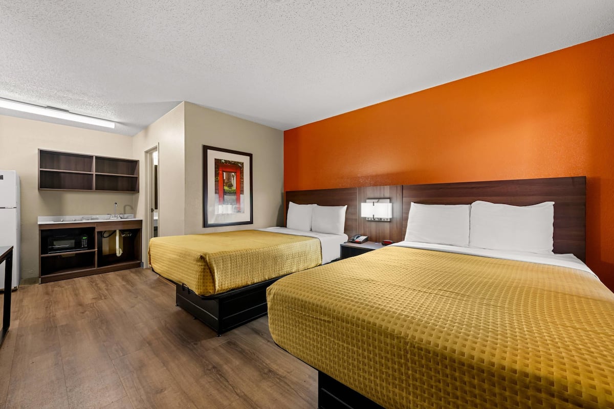 A hotel room with two beds, a desk, and a microwave.