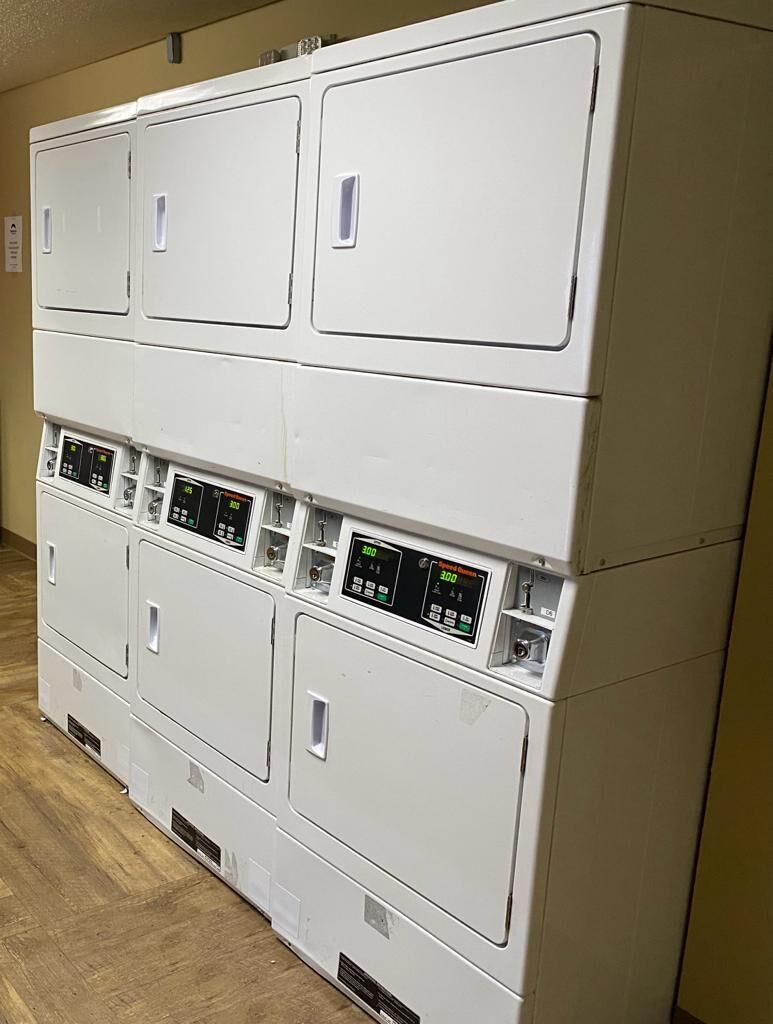 A row of stacked laundry machines with control panels.